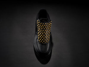 Black sneaker with gold spike overlay for edgy custom style.