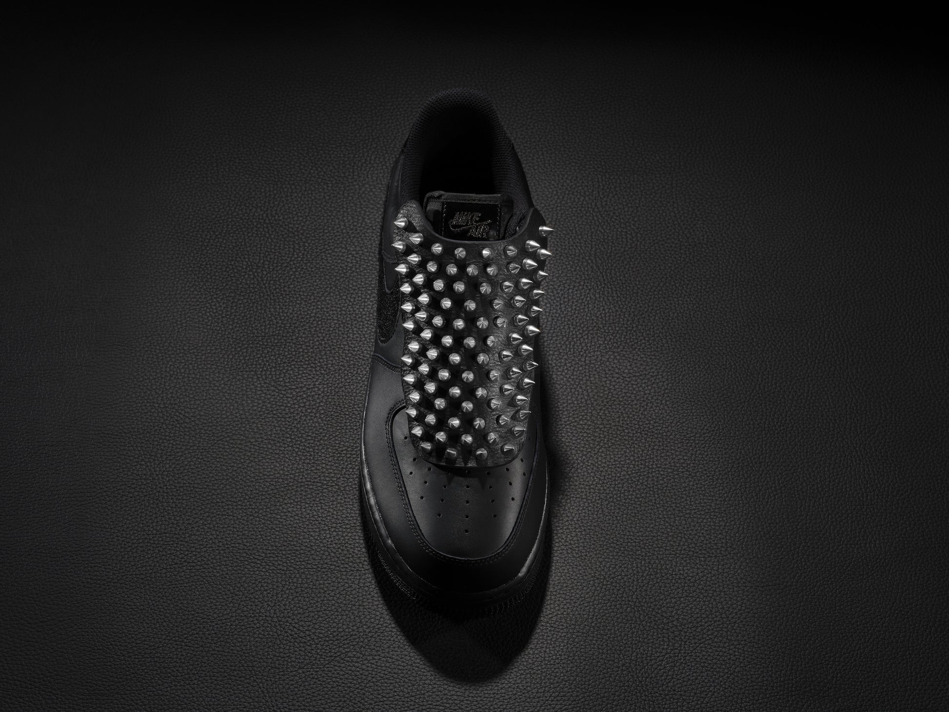 Black sneaker with silver spike overlay for edgy custom style.
