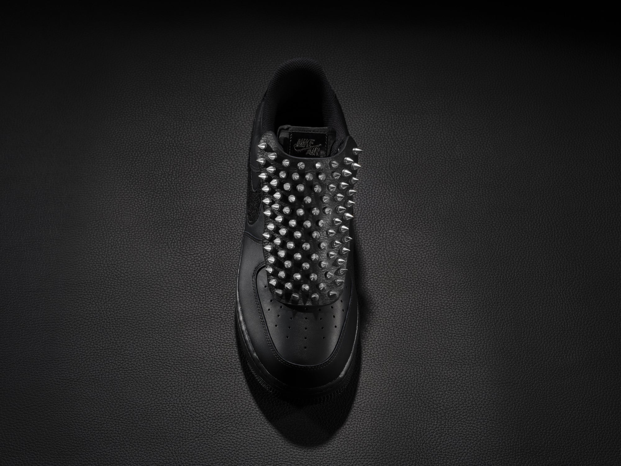 Black sneaker with silver spike overlay for edgy custom style.